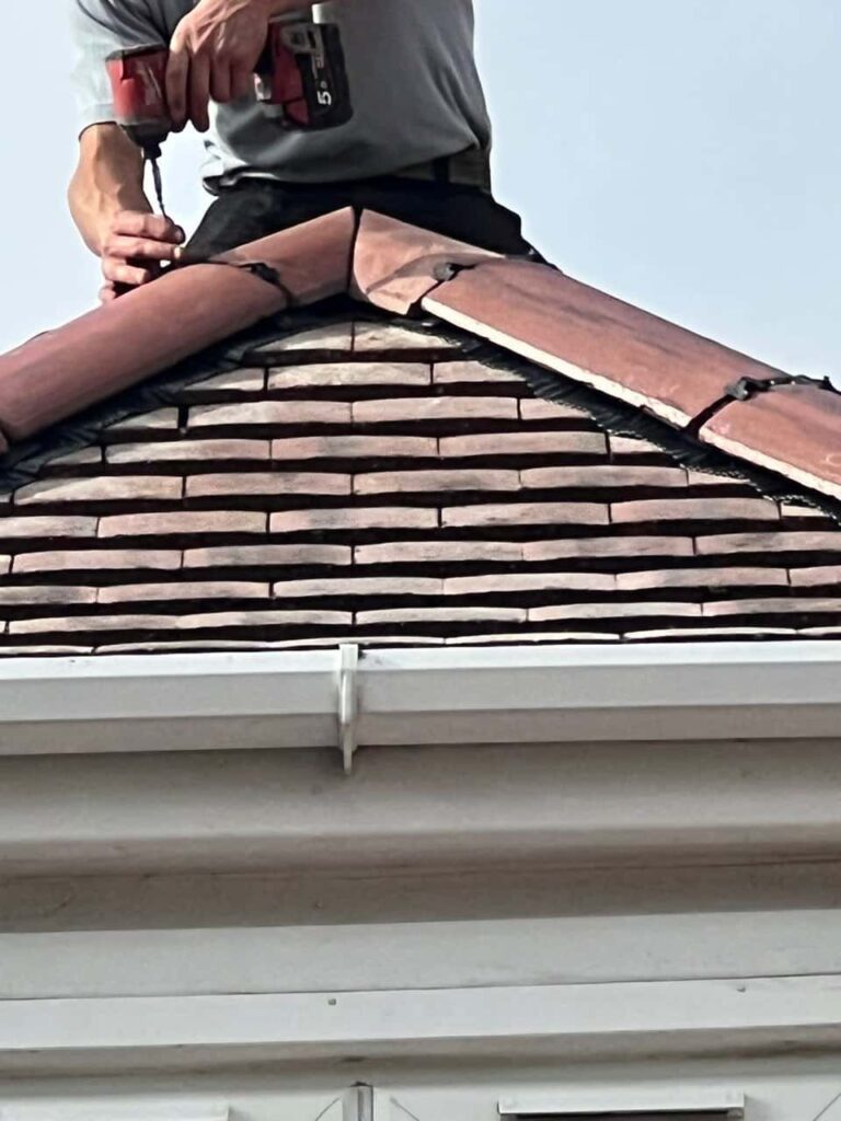 This is a photo of one of the operatives of MCM Roofing Repairs Sherborne installing new ridge tiles