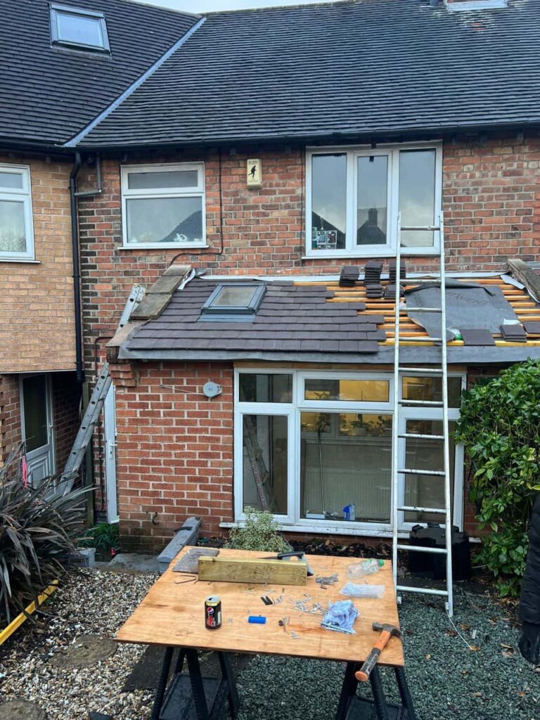 This is a photo of a roof extension that is having new roof tiles installed. This is a photo taken from the roof ridge looking down a tiled pitched roof on to a flat roof. Works carried out by MCM Roofing Repairs Sherborne